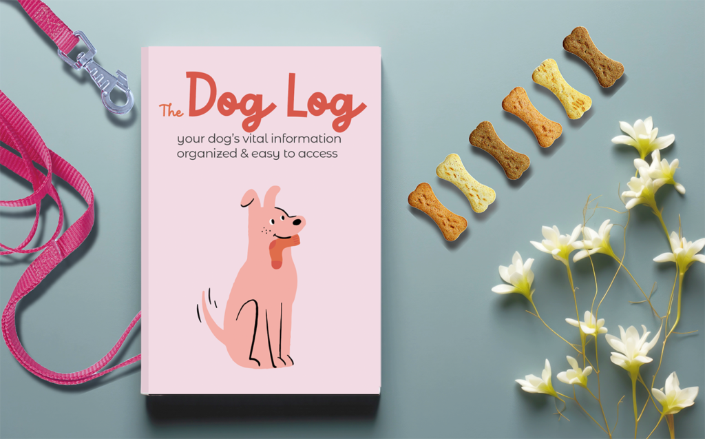 copy of the dog care and health tracker called The Dog Log (pink cover, cartoon picture of a dog) with dog items and flower background.