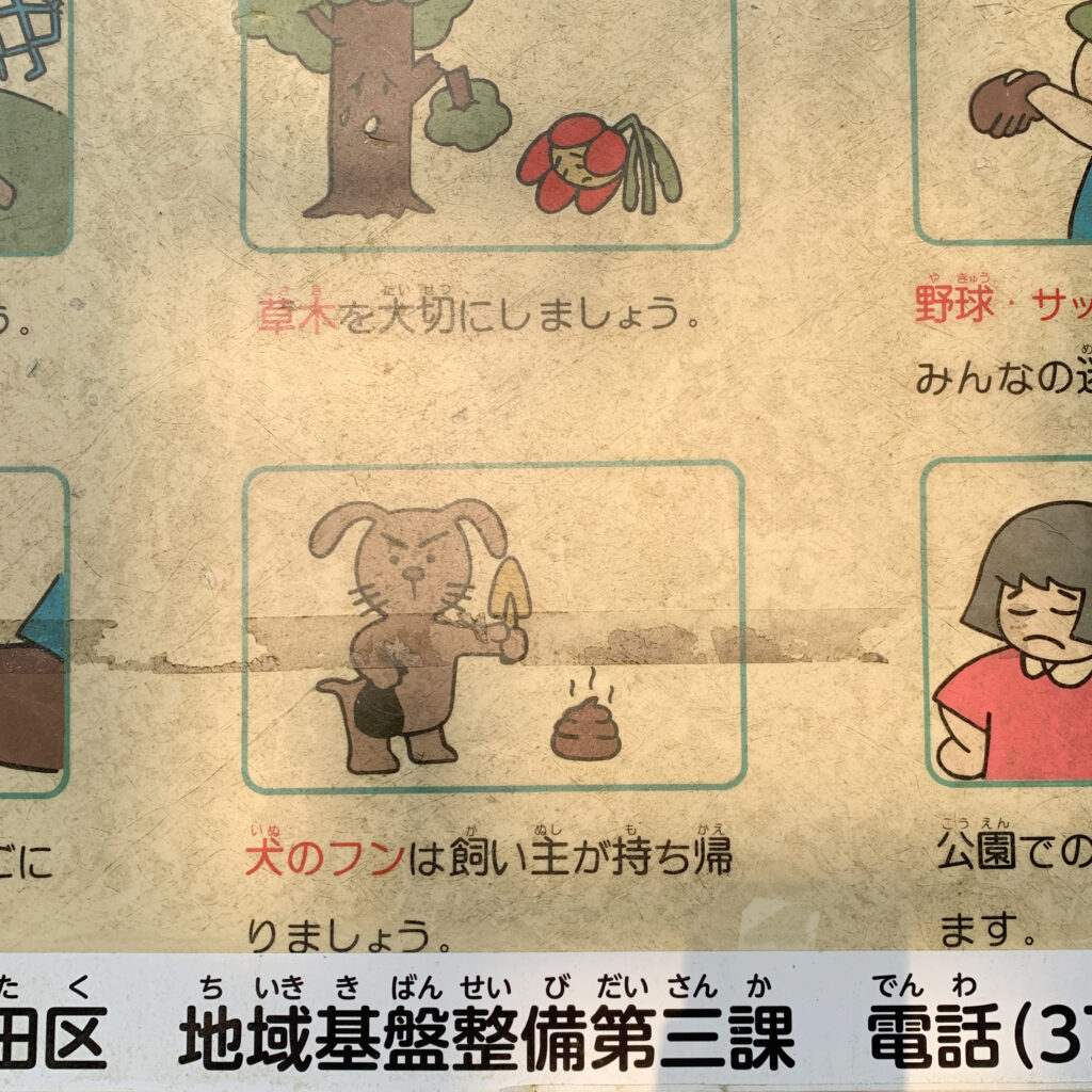 Sing of park rules with cartoons to help explain in a public park in Ota-ku. Main image of a dog holding a mini shovel, a bag and about to pick up dog waste. The text underneath reads: Dog owners must take their dog's waste with them.